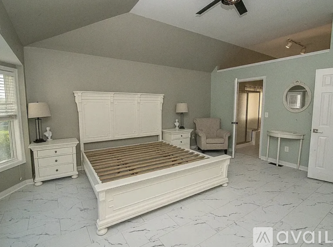 A bedroom with a large bed, a dresser, and a chair.