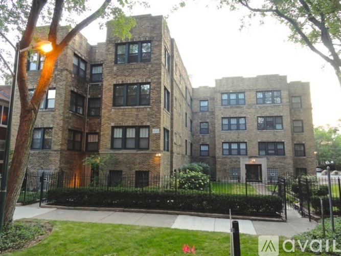 A large brick building with a black fence in front.