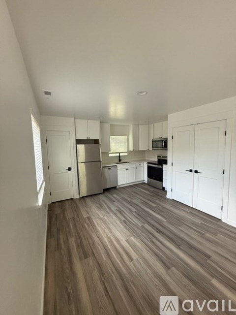A kitchen with white cabinets and a wooden floor.