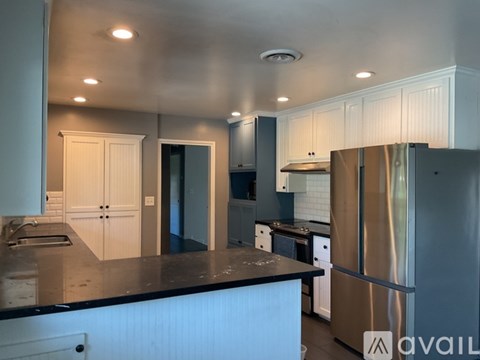 A kitchen with a black countertop and stainless steel appliances.