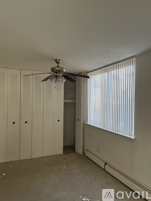 A room with a ceiling fan and a window with blinds.
