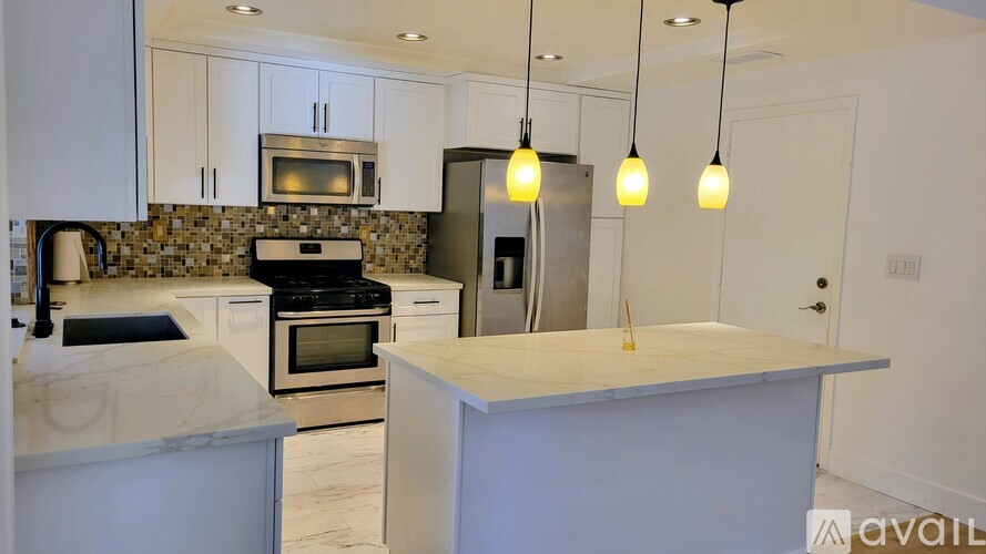 A kitchen with a marble countertop and stainless steel appliances.