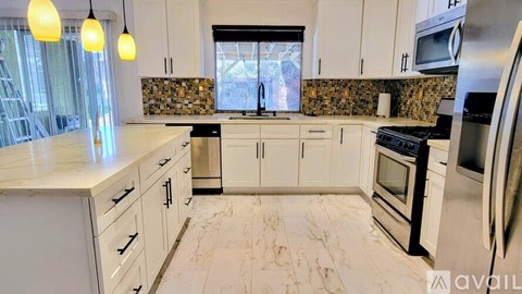 A kitchen with white cabinets and a marble countertop.
