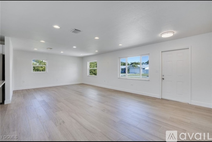A spacious room with wooden flooring and white walls.