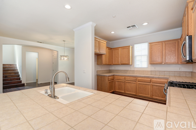 A large, empty kitchen with wooden cabinets and a stainless steel refrigerator.