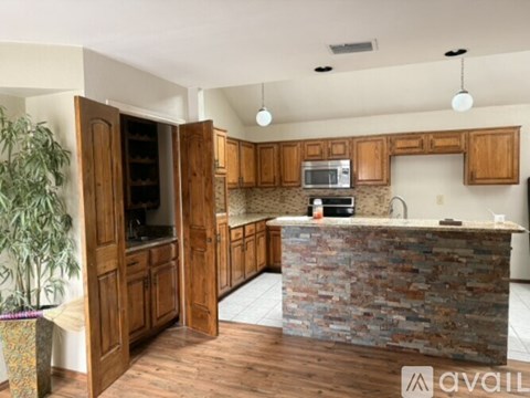 A kitchen with wooden cabinets and a stone counter.