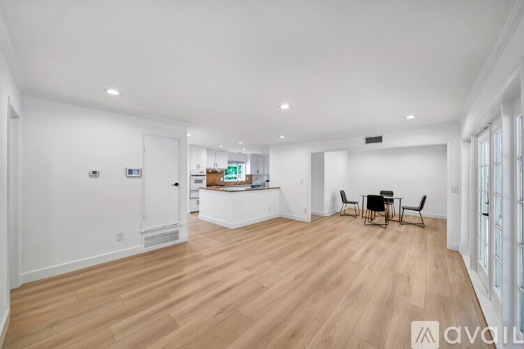 A spacious room with wooden flooring and a dining table set up.