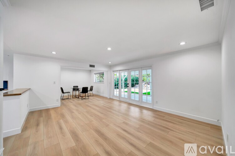 A spacious living room with wooden flooring and a large window overlooking a garden.