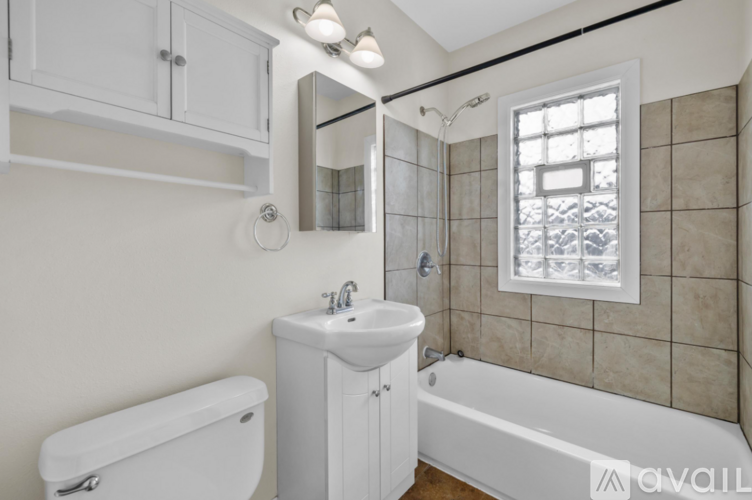 A white bathroom with a tub, sink, and mirror.