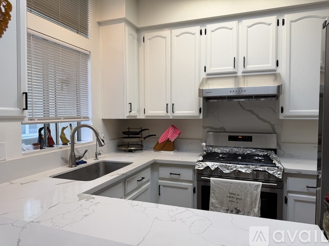 A kitchen with white cabinets and a marble countertop.