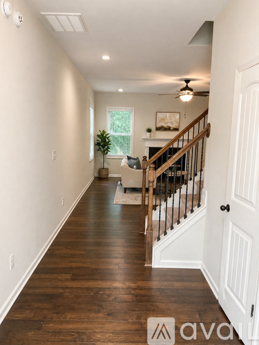 A hallway with a wooden floor and a staircase.