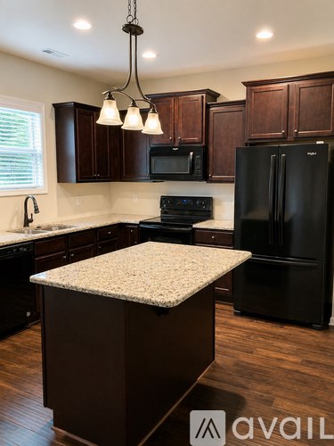 A kitchen with dark wood cabinets and black appliances.