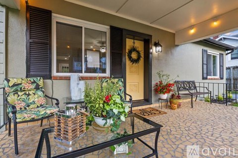 A patio with a glass table and chairs, a wreath on the door, and potted plants.