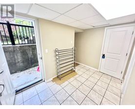 A room with a white door, a window with a view of a fence and trees, and a tiled floor.