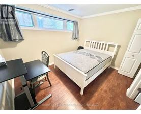 A bedroom with a white bed and a black desk.