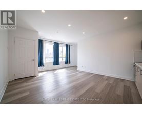 A spacious room with wooden flooring and a window with blue curtains.