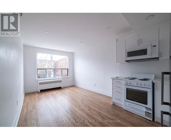 A spacious room with wooden flooring and a window with blue curtains.