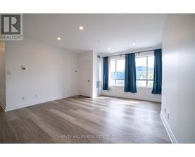 A spacious room with wooden flooring and a window with blue curtains.