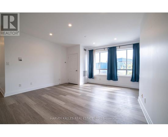 A spacious room with wooden flooring and a window with blue curtains.