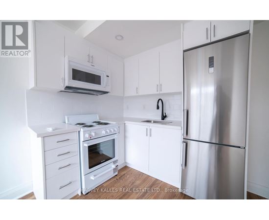 A kitchen with a stove top oven, microwave, dishwasher, and refrigerator.