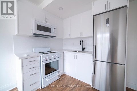 A kitchen with a stove top oven, microwave, dishwasher, and refrigerator.