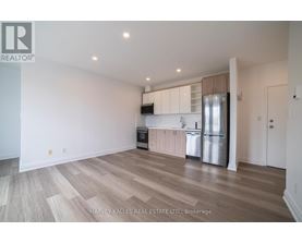 A spacious kitchen with wooden flooring and stainless steel appliances.