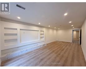 A spacious room with wood flooring and white walls.