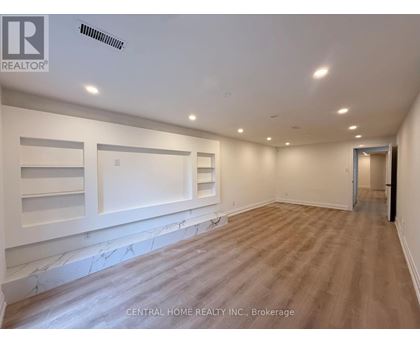 A spacious room with wood flooring and white walls.