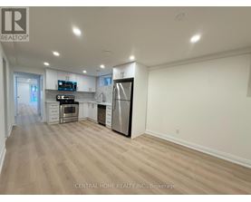 A spacious kitchen with wood flooring and white walls.