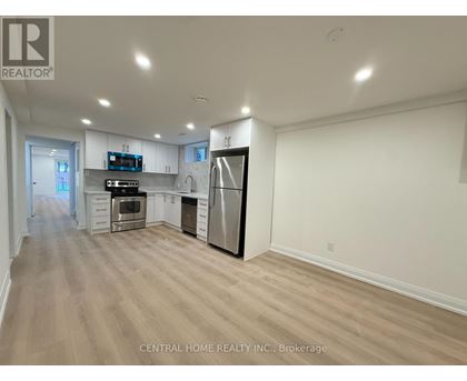 A spacious kitchen with wood flooring and white walls.