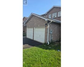 A house with a white garage door and a brick wall.