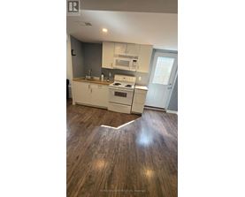 A kitchen with white cabinets and a wood floor.