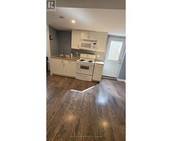 A kitchen with white cabinets and a wood floor.