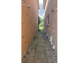 A narrow alley with a concrete path and brick walls on either side.