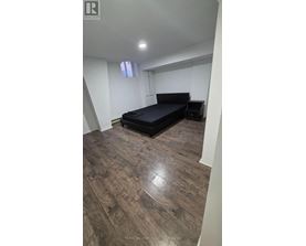 A bedroom with a bed and wooden flooring.