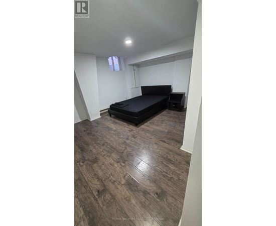 A bedroom with a bed and wooden flooring.