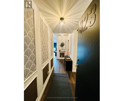 A hallway with a light fixture and a number 323 on the wall.