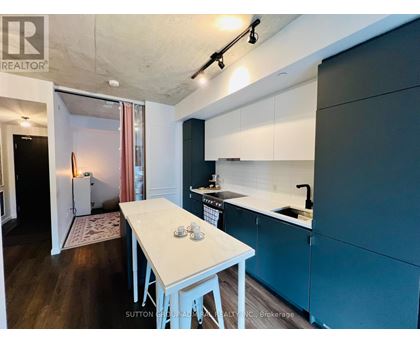 A kitchen with a table and chairs in the foreground and a refrigerator in the background.