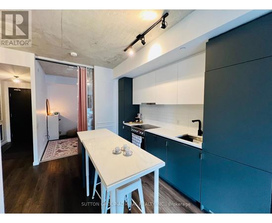 A kitchen with a table and chairs in the foreground and a refrigerator in the background.