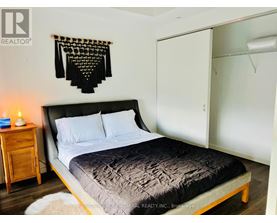A bedroom with a bed, a nightstand, and a wall hanging.