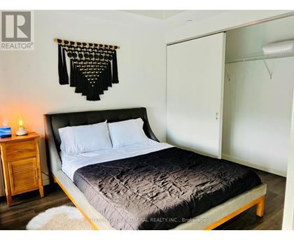 A bedroom with a bed, a nightstand, and a wall hanging.