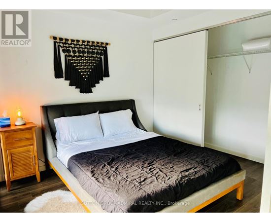 A bedroom with a bed, a nightstand, and a wall hanging.