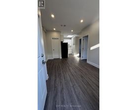 A long hallway with wood floors and white walls.