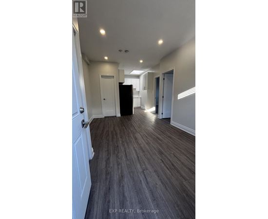A long hallway with wood floors and white walls.