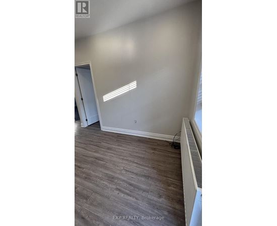 A room with a wooden floor and a white wall with a doorway.