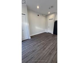 A room with wooden flooring and white walls.