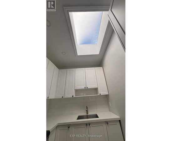 A kitchen with white cabinets and a skylight.