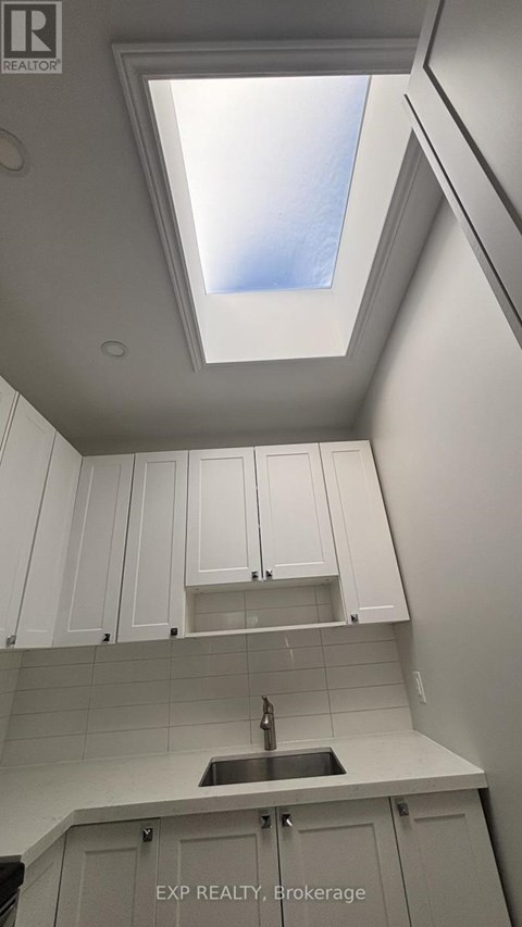 A kitchen with white cabinets and a skylight.