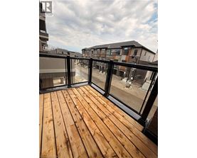 A wooden deck with glass railings overlooks a courtyard.