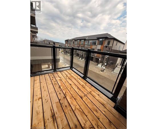 A wooden deck with glass railings overlooks a courtyard.
